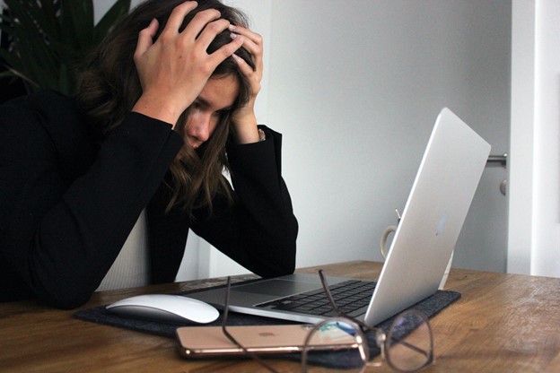 Stressed woman sat at a desk with her head in her hands