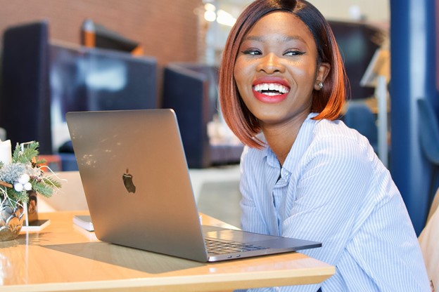 Woman smiling sat at a desk with her laptop