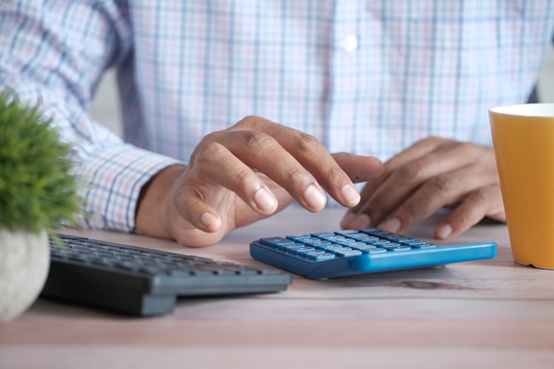 Man sat at a desk, using a calculator