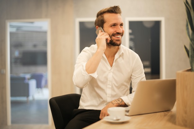 Male professional smiling, and on the phone at his desk