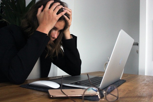 Stressed woman sat at a desk with her head in her hands