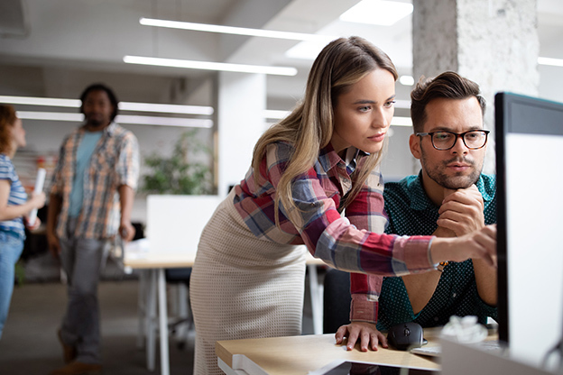 male and female looking at a computer screen in an office environment