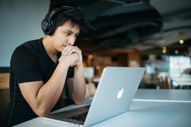 Young man sitting at his desk and viewing his payslip on his laptop