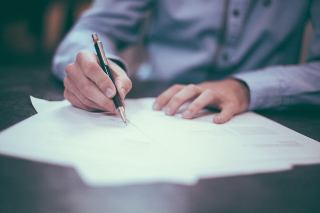 Person filling out paperwork at a table