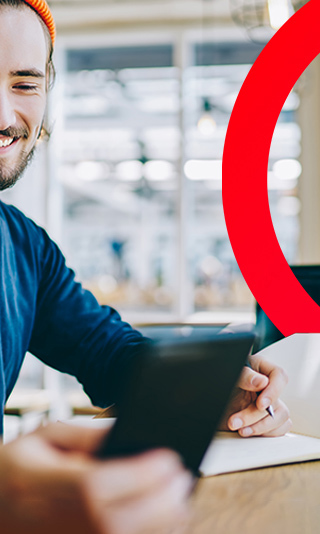 Man smiling at his phone screen as he goes to write in his notepad